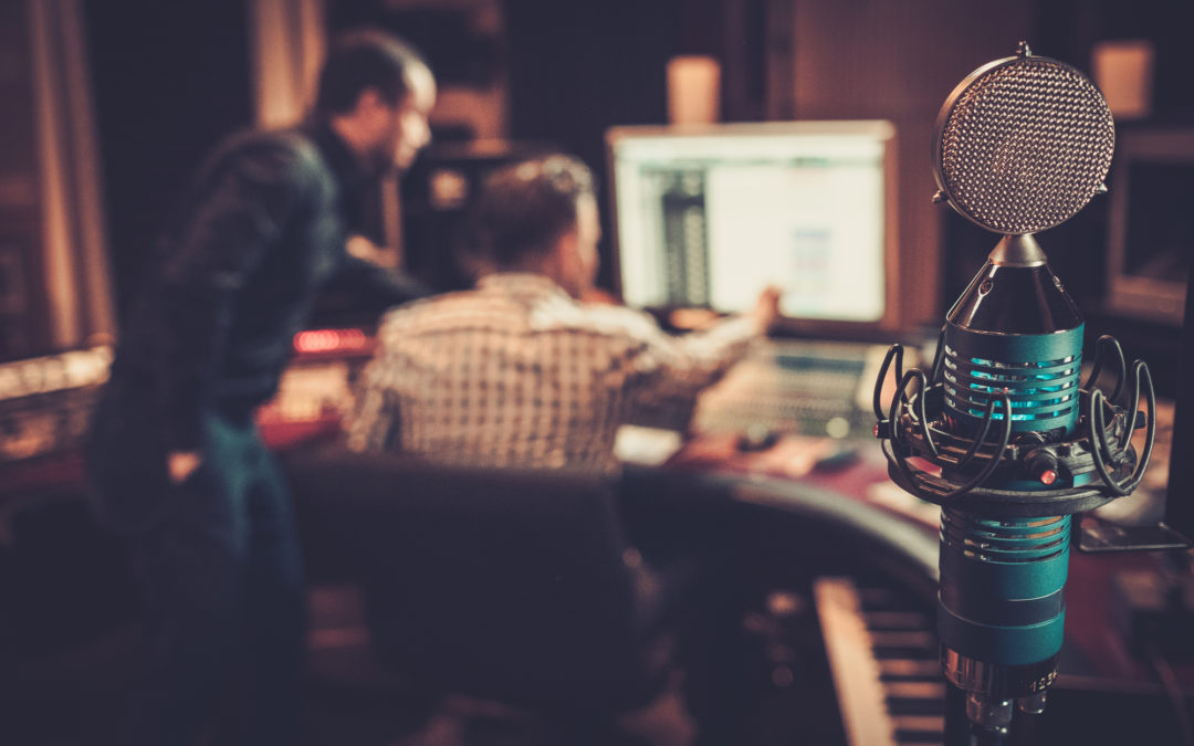 Sound engineer and producer working together at mixing panel in recording studio